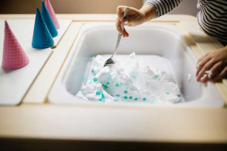Close-up of a child's hands making ice cream in a children's room.の写真素材