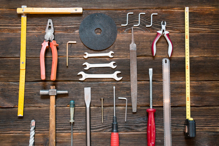 Set of different work tools: screwdriver, pliers, hammer, pliers, handsaw, meter, wrench and other tools over dark wooden background.の写真素材