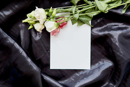 Elegant stationery card with eustoma flowers on black backdrop. Festive creative mock up. Birthday card or advertising place. High quality photo. Top viewの写真素材