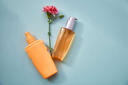 Cosmetics in the form of a flower and a pink flower on blue background on blue background. A modern conceptual female plot. Copy spaceの写真素材