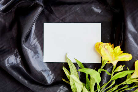Mock up stationery card among flowers on black background. Summer feminine concept. Beauty elegant style concept. High quality photo.の写真素材