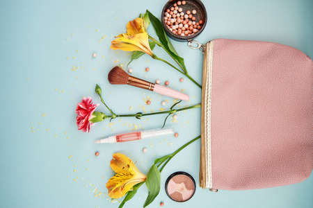 Explosion of makeup cosmetic accessories from pink clutch. Brushes for makeup, powder, make up shadows and flowers. High quality photoの写真素材