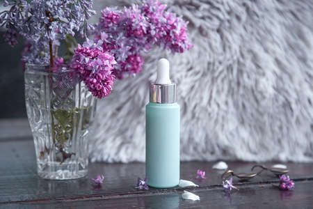 Mock up of turquoise anti aging serum droplet. Natural wellness cosmetic product in front of Scandinavian interior with lilac flower. High quality photoの写真素材