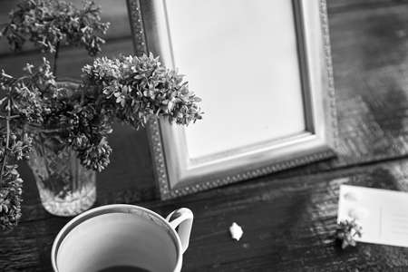 Vintage black and white flat lay mock up frame with lilac flowers, cup and card. Copy space. Trendy template.の写真素材