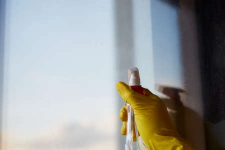Spring cleaning concept. Sanitize and cleanliness through the pandemic. Hand is washing window at...