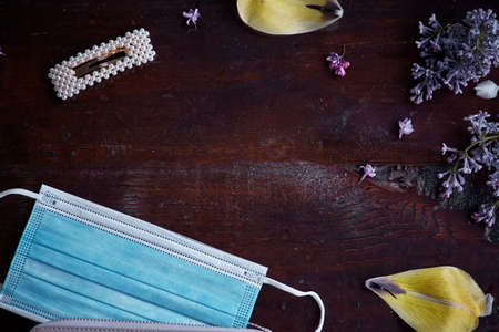 Protective medical mask during the pandemic surrounded by flowers and feminine accessories. Hope and protection concept.の写真素材