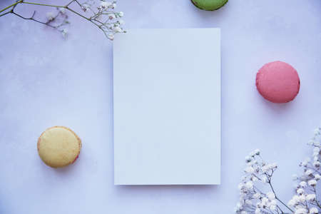 Mock up of stationery card on purple vintage surface with bright colorful macaroons, gypsophila....