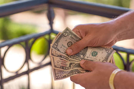 Man counts dollars in his hands. Close up of a stack of american dollar banknotes. Money background. Financial, business, investment and economical concept. High quality photoの写真素材