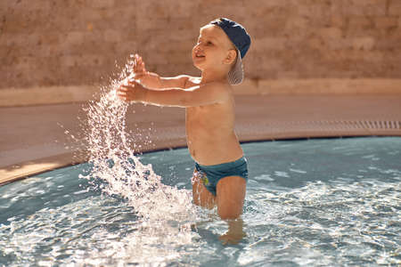 Caucasian cute toddler swims and have fun in small pool for swimming. Concept of summer vacations and fun. High quality photo. Copy spaceの写真素材