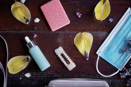 Stylish women clutch explosion with mask, dropper glass bottle, mirror, hairpin surrounded by yellow...