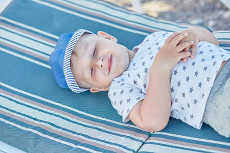 Caucasian funny cute baby boy have a rest on sunbed near swimming pool. Summer vacations and fun...