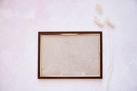 Brown frame mockup on vintage surface. Vintage frame with dry Lagurus ovatus grass and gipsophila....