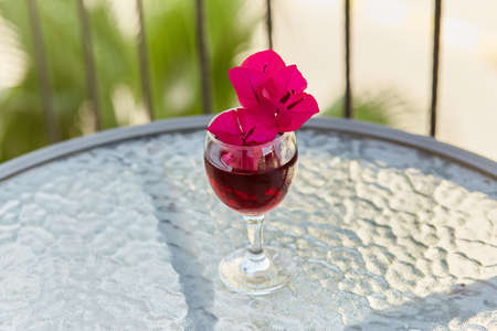 Elegant and colorful glass of red wine. Decorative minimalist pink flowers of bougainvillea in a glass. Festive holiday conceptの写真素材