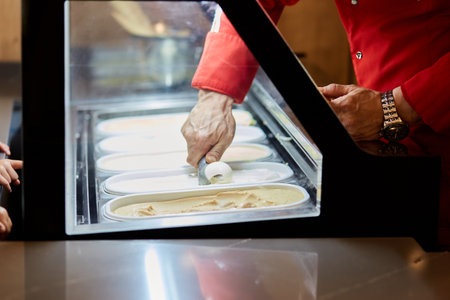 Filling a waffle cone with ice cream. Large assortment of different ice cream. Serving gelato.