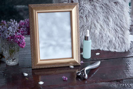 Elegant mock up frame with lilac flowers, face massager, dropper glass turquoise bottle with shadows. Modern Scandinavian interior, minimalist concept. Copy space. Trendy template.の写真素材