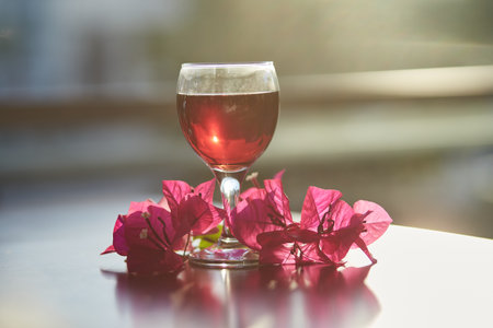 Glass of red wine on blurred mountain background. Decorations of pink bougainvillea flowers with sunlight. Blue hour photography. Romantic dinner concept. Copy space.の写真素材