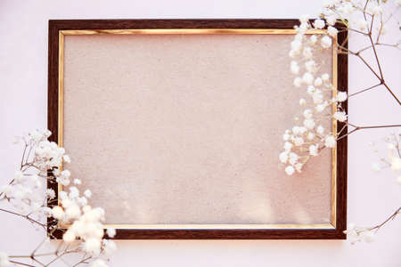 Elegant brown frame mockup on vintage surface. Vintage frame with gypsophila. Beige background, Scandinavian interior. Minimalist Place for advertising, thank you or wishing. Top viewの写真素材