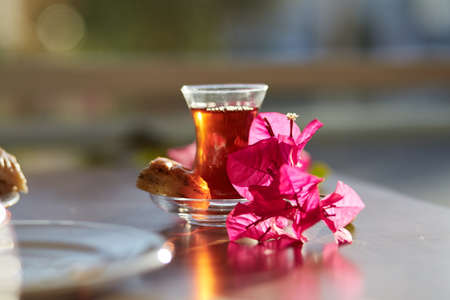Turkish delight and traditional glass of turkish tea with bougainvillea flowers. Romantic dinner concept. Relaxing, calming drink Travel Turkey concept. Bright relaxing drink. High quality photoの写真素材