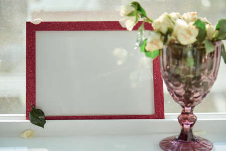 Pink frame mock up with sunlight and wineglass with white roses. Selective focus. High quality photoの写真素材