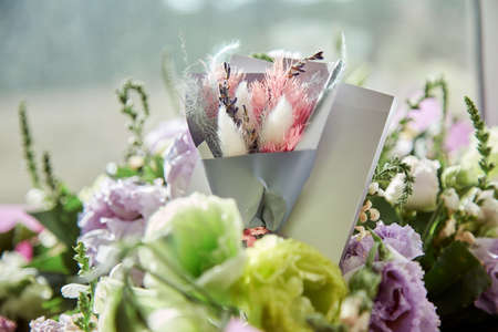 Present post card close up with delicate big flowers bouquet of eustoma and dry flowers under day light with dry colorful Lagurus ovatus grass. Flowers delivery and present concept. High quality photoの写真素材