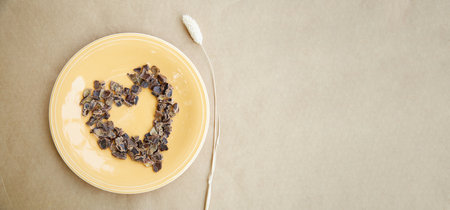 Carob - plant-based alternative - natural product on the plate with dry Lagurus ovatus grass in a shape of heart. Extra wide banner. Organic antioxidants and protein. Top view. High quality photoの写真素材