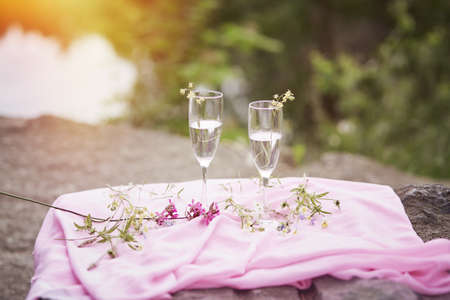 Autumn picnic. Champagne with wildflowers on the stove. Photo picnic on the nature with sunlight. Celebrating life and solitude concept. Glasses with champagne. Copy space. High quality photoの写真素材