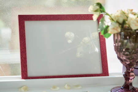 Pink frame mock up with sunlight and wineglass with white roses. Selective focus. High quality photo