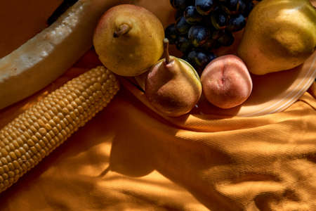 Creative fruits photography: group of grapes, apple, pear, peach, corn and melon on the orange plate...
