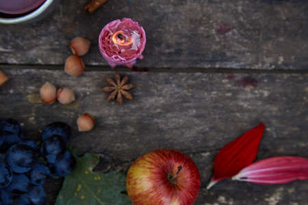 Rustic natural cozy still life of candle, fruits, hazelnuts, anise star and cinnamon sticks. Autumn aesthetic concept, red georgine petals. Cozy home with aromatic candle. Thanksgiving day conceptの写真素材