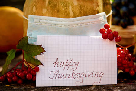 Pumpkin in mask and inscription Happy Thanksgiving. Autumn rustic concept with fruits, vegetables...