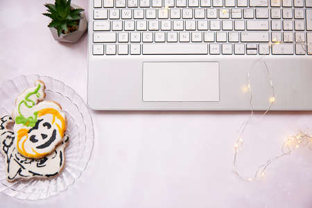 Cozy home office in Halloween : laptop and red cup, homemade cookies in shape of cute pumpkins....