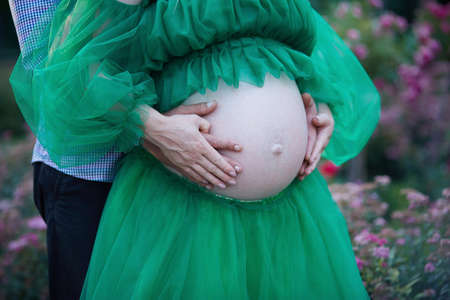 Elegant pregnancy. Tenderness pregnant couple in the garden close up. Big tummy. High quality photoの写真素材