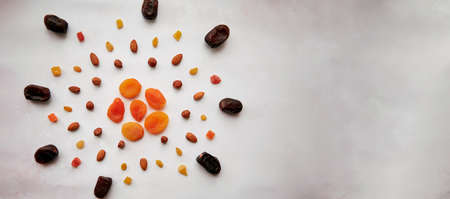 Creative food in shape of sun with dates, dried apricots, hazelnuts, almonds, candied fruits and...
