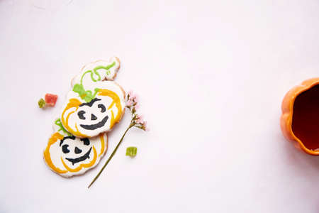 Halloween still life with pumpkin cup with tea and homemade cookies in shape of sweet pumpkins. Bright pink aesthetic autumn holiday or trick or treat concept. Copy space. Home cooking and coziness.の写真素材