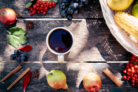 Sunny cozy top view still life with mug of tea, cinnamon sticks, apples, grapes and viburnum in rustic style. Autumn aesthetic concept. Cozy home with warm tea. Thanksgiving Day conceptの写真素材