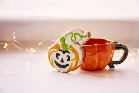 Halloween cookies. Pumpkin cup and homemade cookies in shape of cute pumpkins. Atmospheric aesthetic autumn mood or trick or treat concept. Copy space. Home cooking and coziness. Close up,copy spaceの写真素材