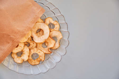 Proper nutrition concept. Paper bag with dried sliced apple chips - healthy trendy snacks on the...