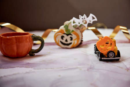 Halloween decors with orange pumpkin mug, handmade cookie, felted pumpkins and yellow retro car. Happy Halloween concept. Copy space. High quality photo.の写真素材