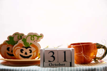 Happy Halloween still life with pumpkin cup and homemade cookies in shape of cute pumpkins and date of Halloween Day. Atmospheric aesthetic autumn holiday concept. Rural life. High quality photoの写真素材