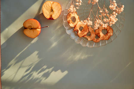 Healthy dried sliced apple chips - wholesome snacks and fresh apples on the plate. Trendy shadows. Top view. Proper nutrition, healthy food concept. Gypsophila flower decoration. High quality photoの写真素材