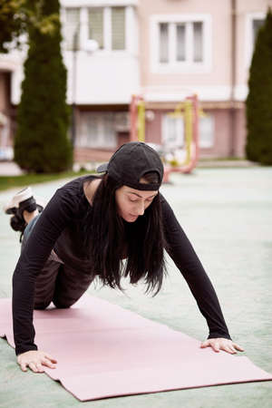Young slim woman doing push up exercise outside. Outdoor workouts. Healthy lifestyle concept....