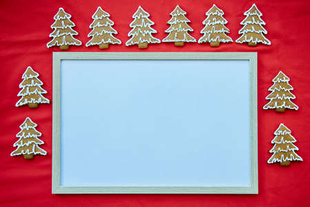 Christmas homemade gingerbread cookies with mock up frame. Festive aesthetic card on red fabric. Christmas atmosphere. Merry Christmas and home coziness concept. High quality photoの写真素材