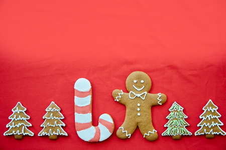 Christmas handmade gingerbread cookies with copy space on red fabric background. Homemade baking background. Festive card with aesthetic Christmas atmosphere. Merry Christmas and home coziness conceptの写真素材