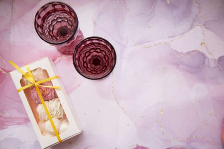 Festive glasses of wine and tender pink and white marshmallow with decoration of fluid art. Feminine...