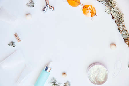 Trendy face care cosmetics background on white background. Serum, mockup cream, massager and sunglasses. Natural eco forest moss. Hyaluronic and moisturizing gel. Dermatology cosmetics. Copy space. High quality photoの写真素材