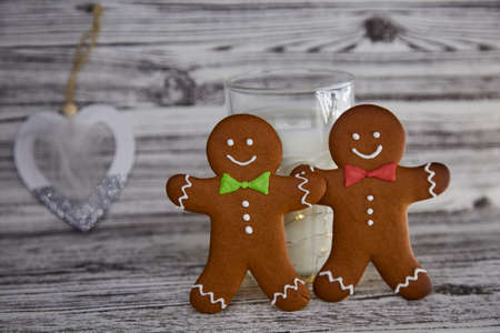 Milk with gingerbread cookies for Santa. Handmade fresh cookies and glass with milk on the vintage wooden table. Christmas traditions. Aesthetic atmosphere and festive Christmas background.の写真素材