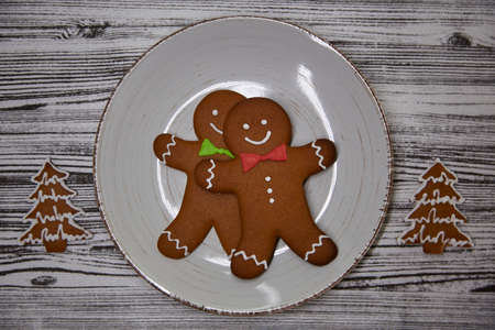 Cute handmade gingerbread cookies on vintage beige plate on the wooden table. Table setting. Top...