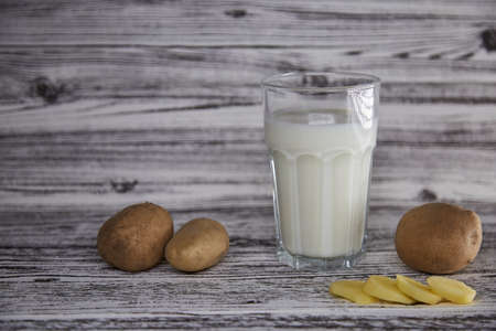 Lactose free, environment friendly potato milk and potato on the plate on the table. Alternative, non-dairy milk. Tile classic background. Copy space. High quality photoの写真素材