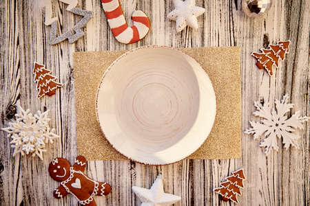 Served festive Christmas table. Vintage beige plate mock up, handmade gingerbreads, cookies, Christmas decorations on the table. Trendy Christmas tree toys. Top view. Aesthetic mockup. High quality photoの写真素材