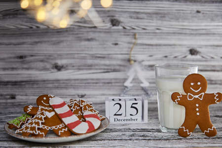 Fresh handmade baking cookies and glass of milk on wooden vintage table. Fluffy trendy Christmas decorations and calendar. Aesthetic atmosphere. Cute Christmas tradition: milk for Santa. Copy space.の写真素材